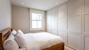 Quarto com cama, janela e armários embutidos.