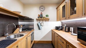 Uma cozinha moderna com armários de madeira, eletrodomésticos de aço inoxidável e um relógio na parede.