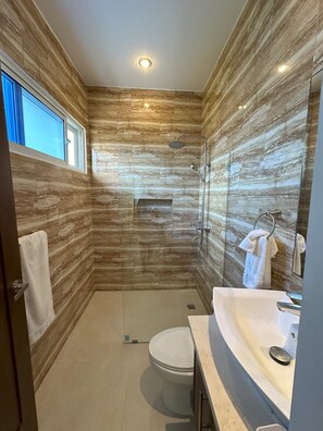 Ein modernes Badezimmer mit einer Duschkabine, einer Toilette und einem Waschtisch.