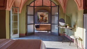 Une chambre avec un grand lit, une coiffeuse avec un miroir et un tableau accroché au mur.