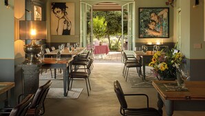 Un grand espace dédié à la salle à manger, avec plusieurs tables et chaises, une grande fenêtre donnant sur l’extérieur et un tableau accroché au mur.
