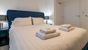 A neatly made bed with white linens and two folded towels on the side. - Charming Coastal Retreat – 1-Bedroom Flat in Blyth - Pass the Keys (Blyth)