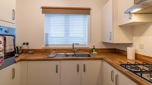 A compact kitchen with a built-in oven, a sink, and a gas stove. - Charming Coastal Retreat – 1-Bedroom Flat in Blyth - Pass the Keys (Blyth)