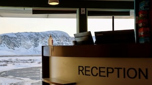 Una mesa de recepción con un cartel que dice 'RECEPTION', una computadora portátil y una botella encima.