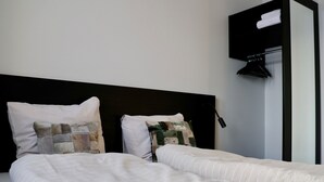 Una cama bien hecha con ropa de cama a rayas y dos almohadas decorativas.