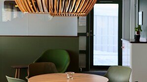 Un interior moderno con una mesa redonda de madera, sillas verdes y una lámpara colgante original.