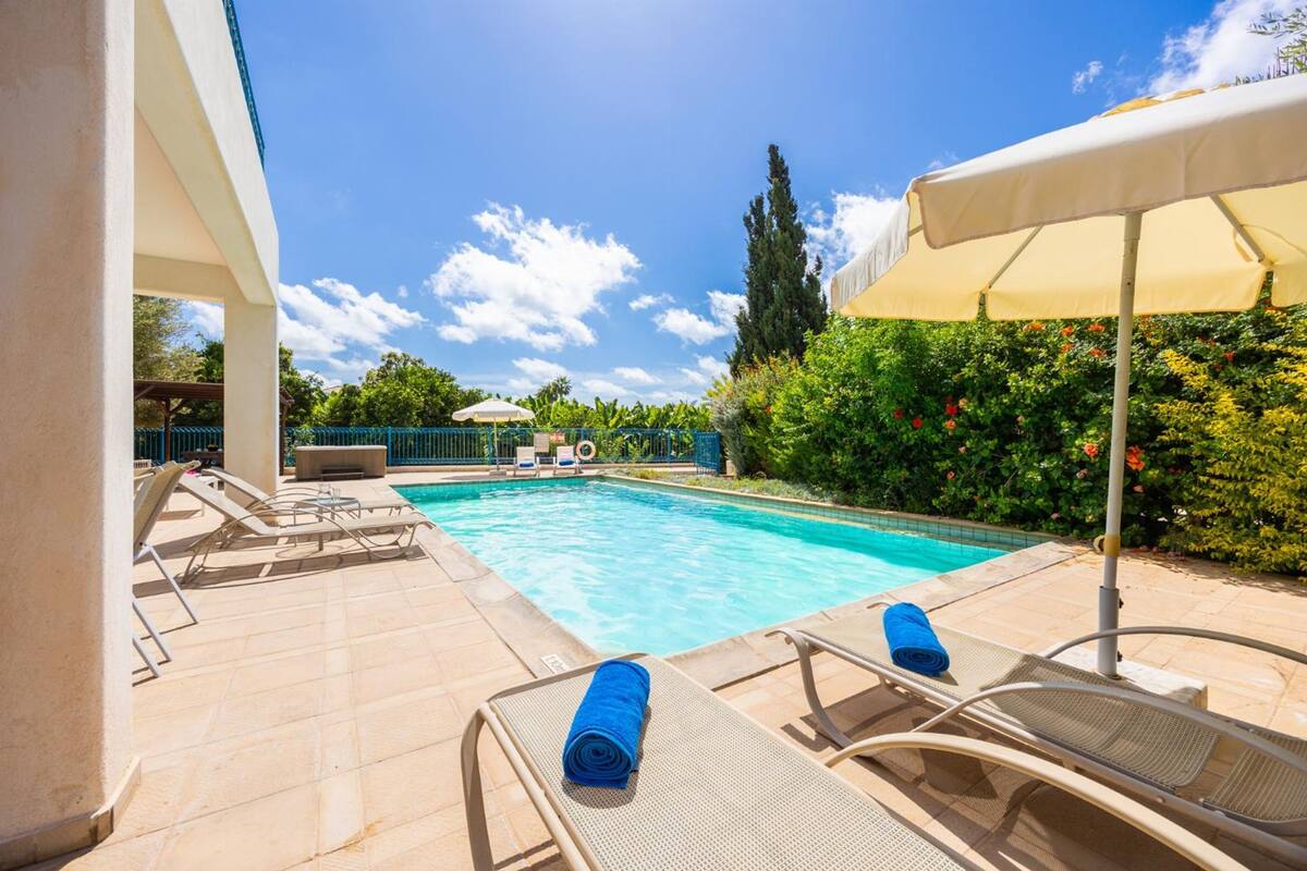 Una piscina con sillas de descanso y una sombrilla.