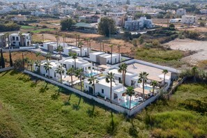 A modern residential complex with multiple white buildings, a swimming pool, and palm trees.