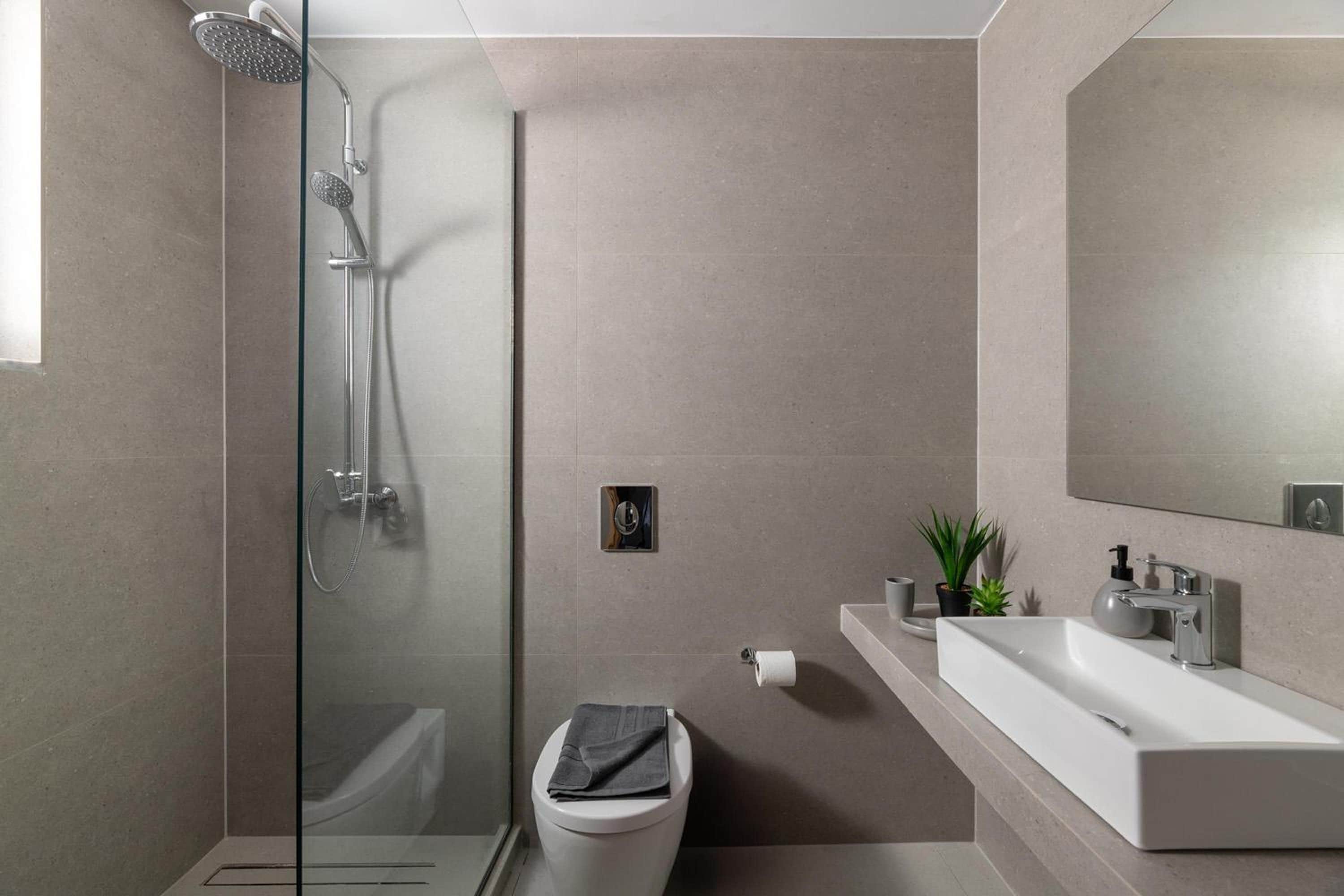 A modern bathroom with a glass-enclosed shower, a toilet, and a vanity with a sink and mirror.