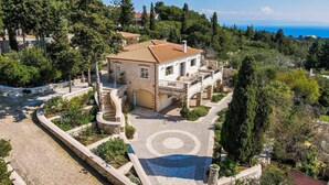 A stone villa with a tiled roof, a central courtyard, and a view of the sea. - Villa Lithos in Paxi (Paxos)