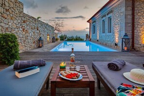 Eine Holzterrasse mit Pool, Steinmauern und einem Gebäude mit Fenstern.