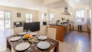 A spacious living area with a dining table set for four, a kitchen with modern appliances, and a cozy seating area with a fireplace. - Villa Livia in Paralimni (Paralimni)