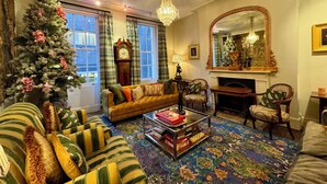 Un salon chaleureux avec une cheminée, un grand miroir et un sapin de Noël.