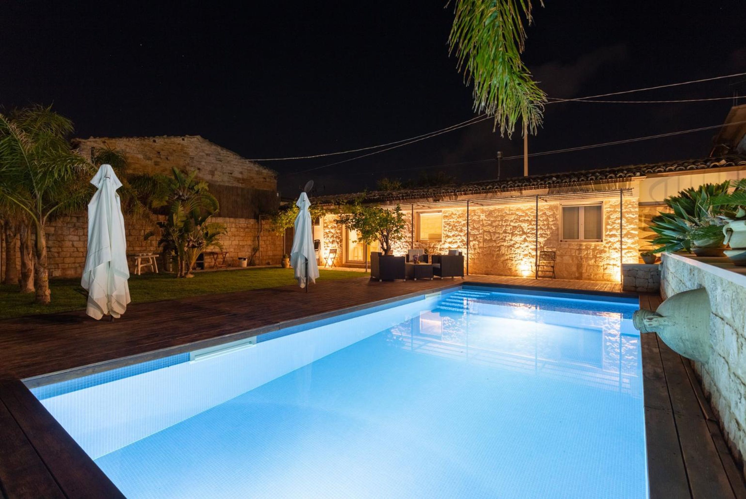 A swimming pool with a stone wall and outdoor seating area.
