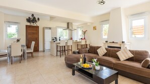 Un espacio habitable amplio con un sofá marrón, una mesa de comedor y una cocina al fondo.