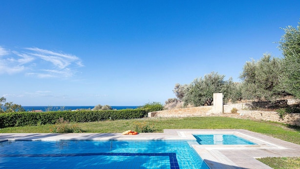 A swimming pool with a view of the sea, surrounded by greenery and a stone wall. - Villa Eleni in Pigianos Kampos (Rethymno)
