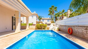 A swimming pool with a stone wall and palm trees in the background. - Villa Claudia in Paralimni (Paralimni)