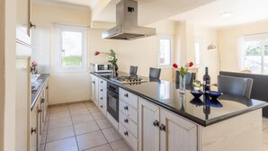 A modern kitchen with a central island, built-in oven, and stainless steel range hood. - Villa Claudia in Paralimni (Paralimni)