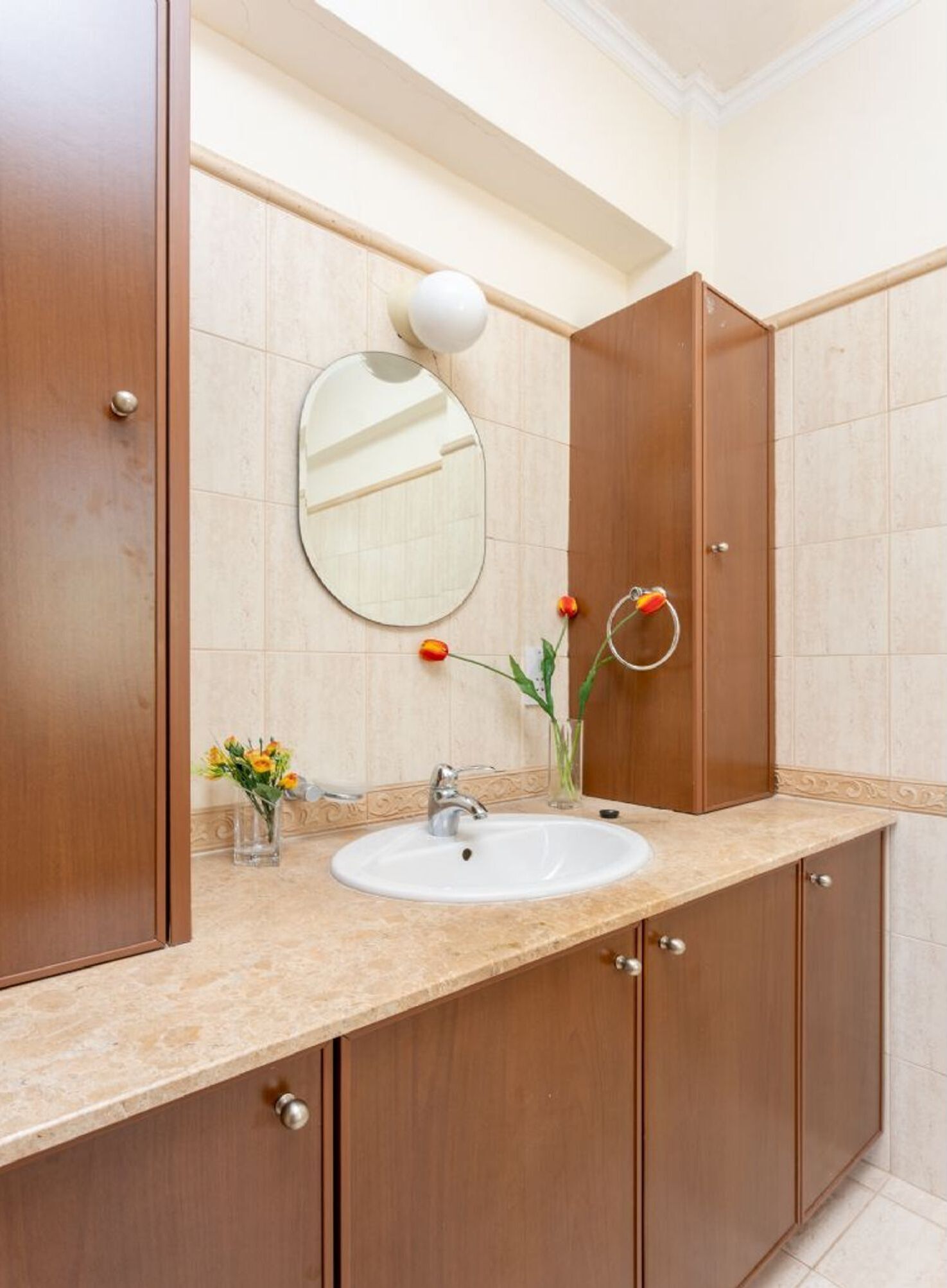 A bathroom with a sink, mirror, and wooden cabinets.