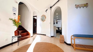 A hallway with a wooden bench, a vase of flowers, and a mirror on the wall. - Villa Cristina 15 in Albufeira (Albufeira)