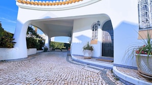 A courtyard with a cobblestone floor, white walls, and arches. There are potted plants and a door with a window. - Villa Cristina 15 in Albufeira (Albufeira)