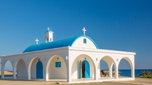 A white church with blue domes and arches, located near a beach. - Villa Koula in Paralimni (Paralimni)