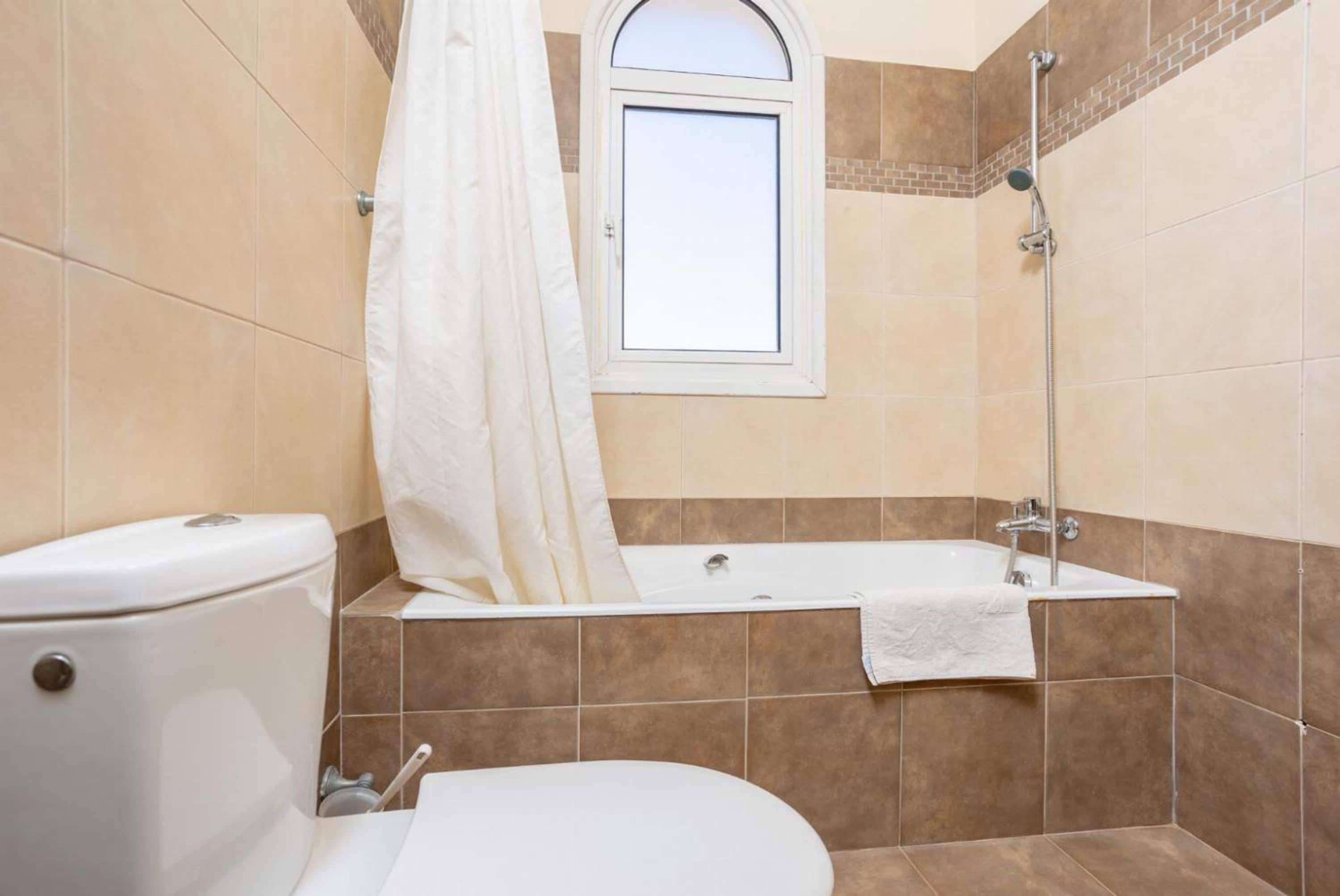 Een badkamer met toilet, bad en douche.
