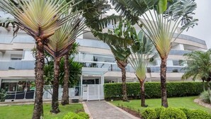 Ein modernes Hotel mit Innenhof, Palmen und einem überdachten Gang.