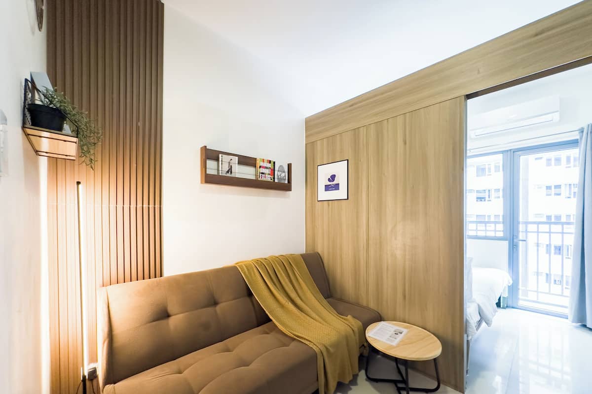 Un salon moderne avec un canapé marron, une petite table ronde et un mur recouvert de panneaux en bois.