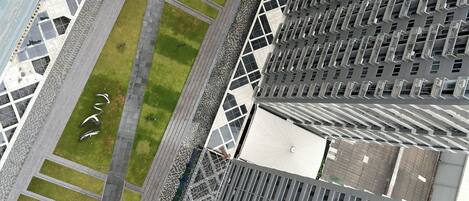 A high-rise building with a rooftop pool, a landscaped area with pathways, and a parking lot.