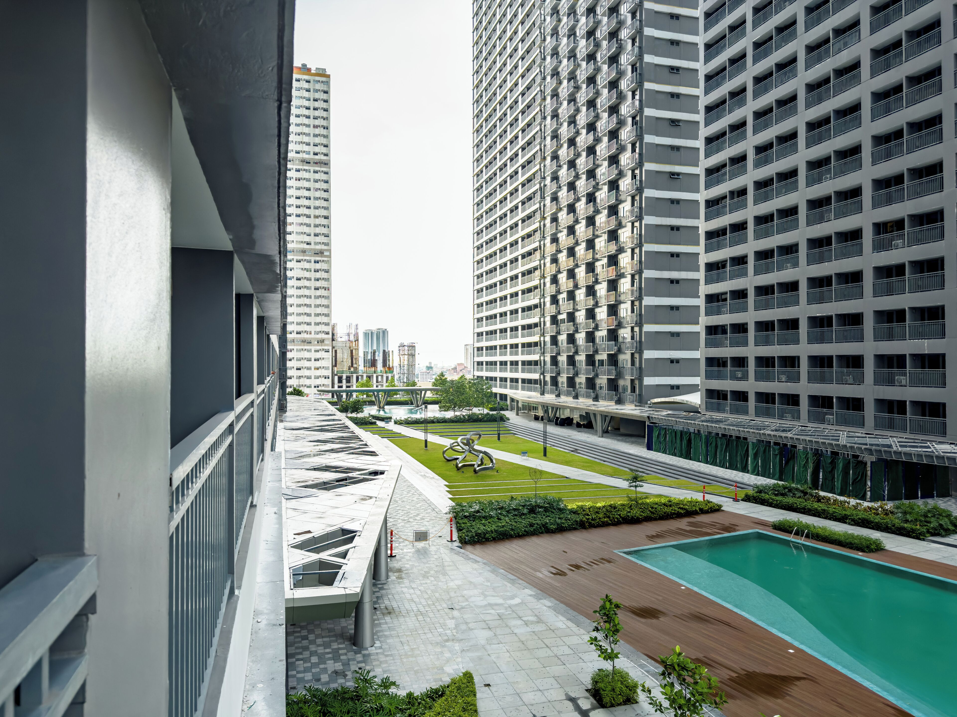 Edificio residencial de gran altura con piscina en la azotea y jardín ajardinado.