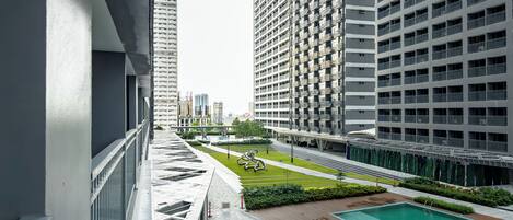 Edificio residencial de gran altura con piscina en la azotea y jardín ajardinado.