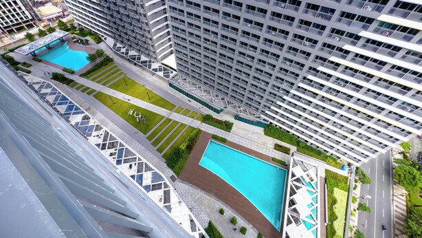 Un edificio alto con molti balconi, una piscina e un giardino curato.