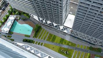 A high-rise building with a rooftop pool, green spaces, and a pedestrian walkway.