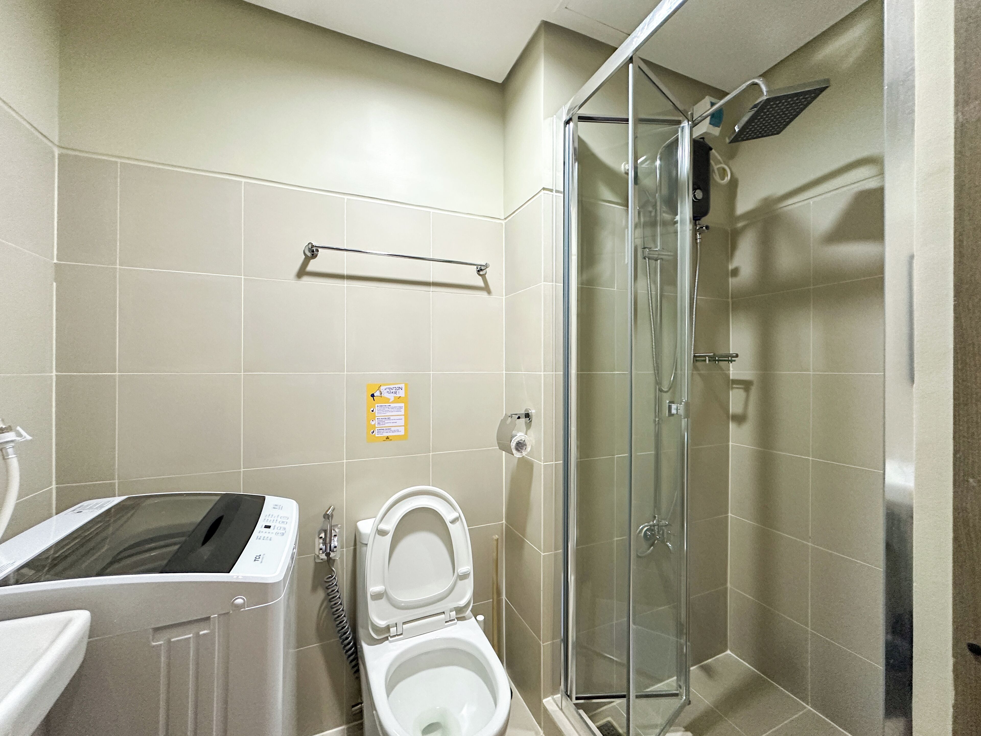 Une salle de bain comprenant des toilettes, une douche à parois de verre et un porte-serviettes.