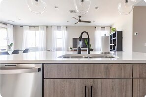 A modern kitchen with a large island, stainless steel appliances, and a ceiling fan. - Forget your worries in this spacious and serene space.  (Casa Grande)