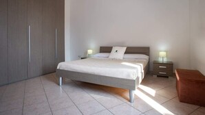 Ein Schlafzimmer mit einem Bett, Nachttischen, einem Kleiderschrank und einer Bank.