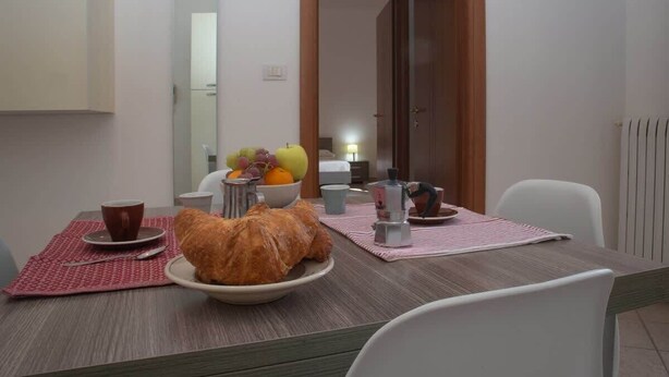 Ein Essbereich mit einem Tisch, gedeckt für das Frühstück, inklusive Croissants, Früchten und Kaffee.