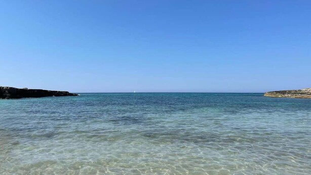 Una vista despejada de una zona costera con aguas tranquilas y formaciones rocosas.