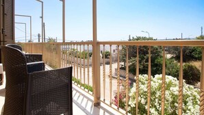 Un balcón con muebles de mimbre y vistas a un jardín con flores blancas.