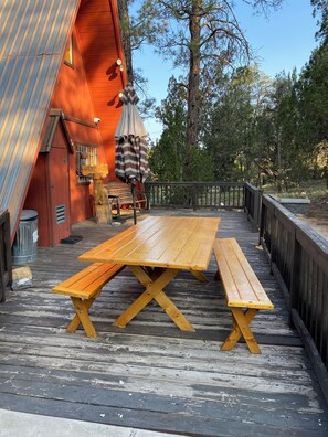 Una terraza de madera con mesas de picnic y un área de estar cubierta.