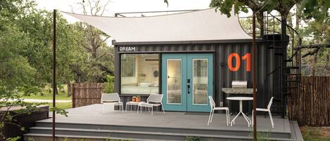A modern outdoor structure labeled "DREAM" with a deck, outdoor seating, and a grill area.