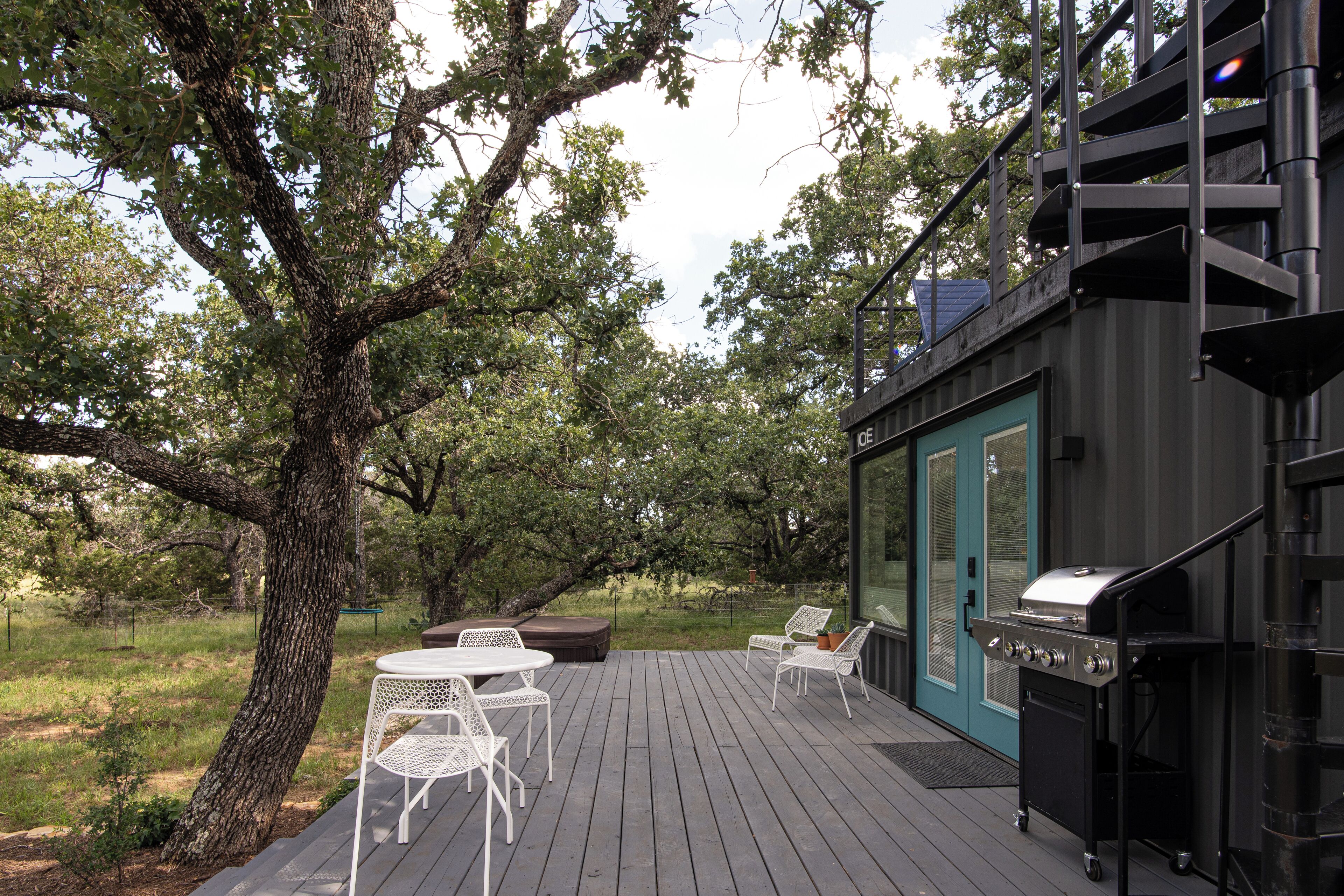 A deck with outdoor seating, a grill, and a view of trees.