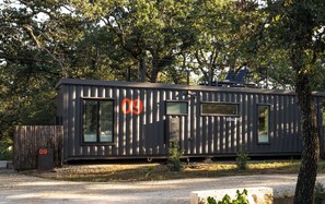 A modern, single-story building with a metal exterior, large windows, and solar panels on the roof.