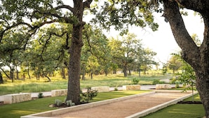A well-maintained garden with mature trees, a rectangular flower bed, and a neatly trimmed lawn. - ParcBlu (Fredericksburg)