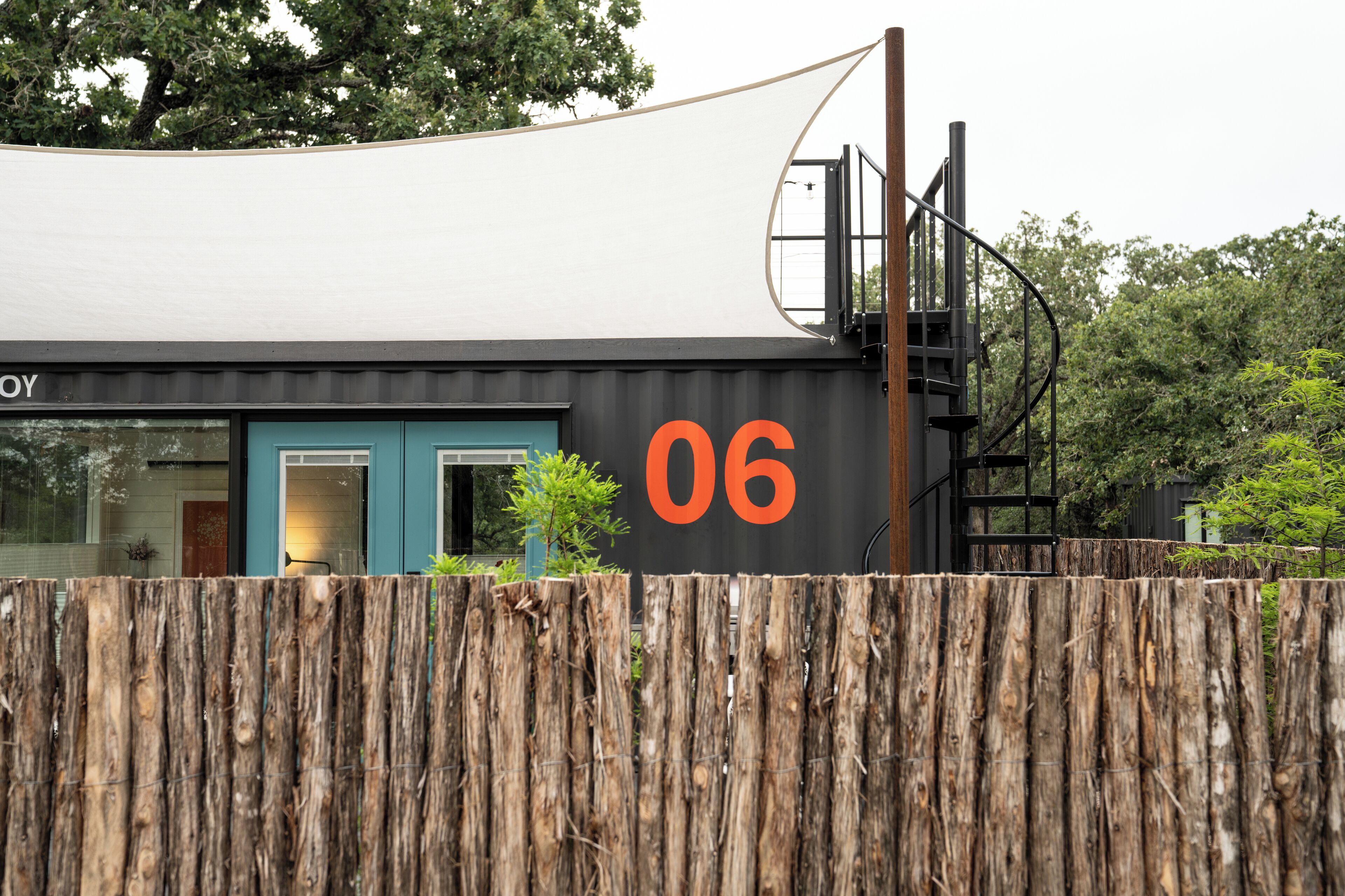 Un edificio moderno con fachada negra y un gran número naranja '06' en la lateral.