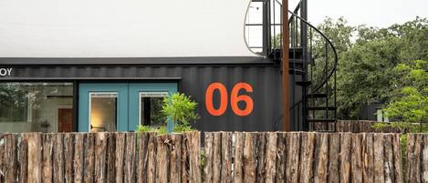 Un edificio moderno con fachada negra y un gran número naranja '06' en la lateral.