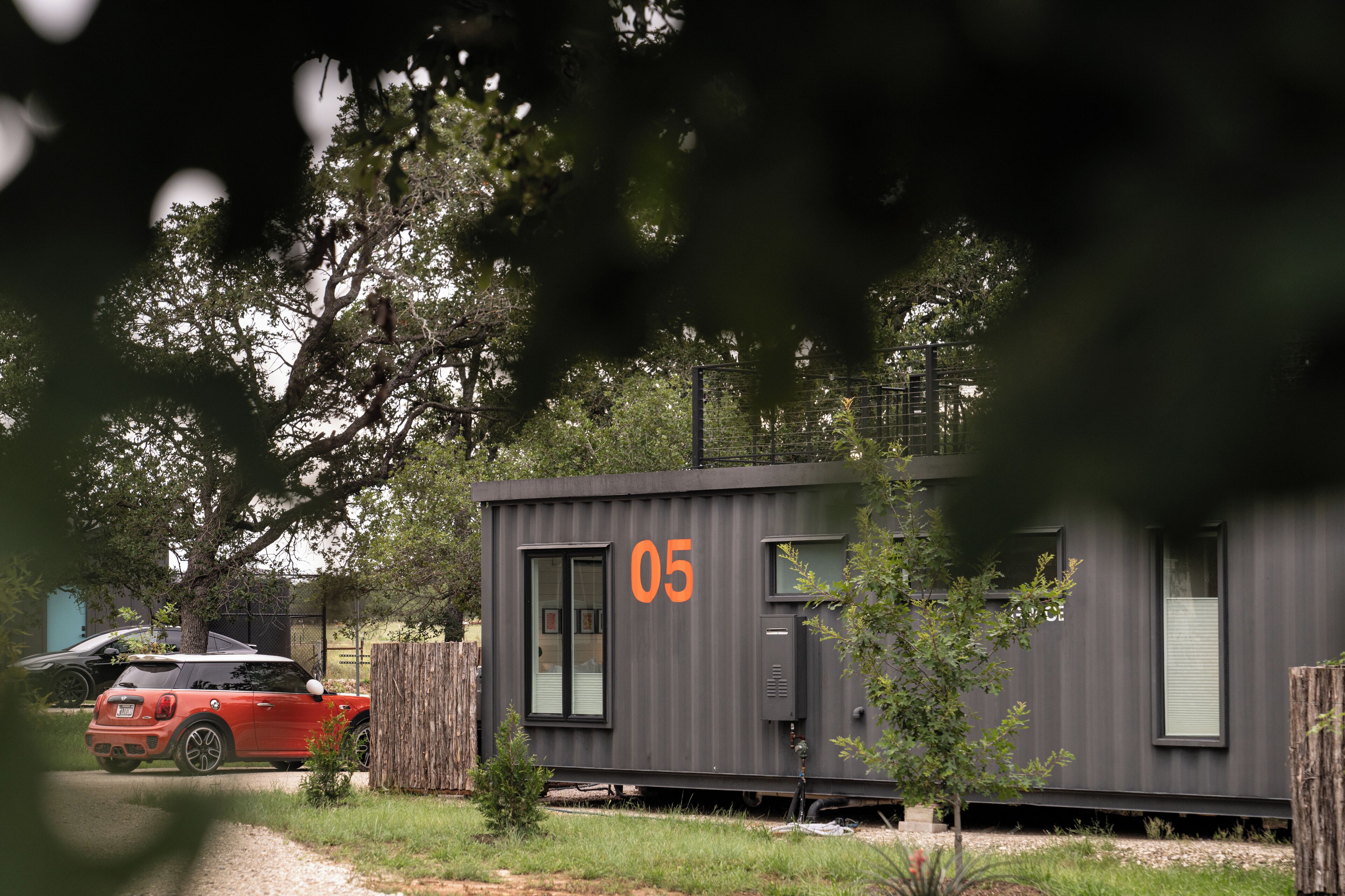 Un bâtiment moderne, de couleur grise, à un seul étage, portant le numéro 05 sur son côté, et situé à côté d’une voie ferrée.