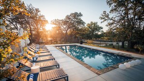 A swimming pool with lounge chairs and a stone border. - ParcBlu (Fredericksburg)