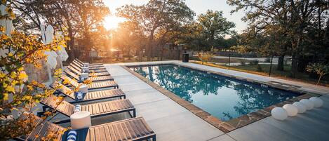 A swimming pool with lounge chairs and a stone border.